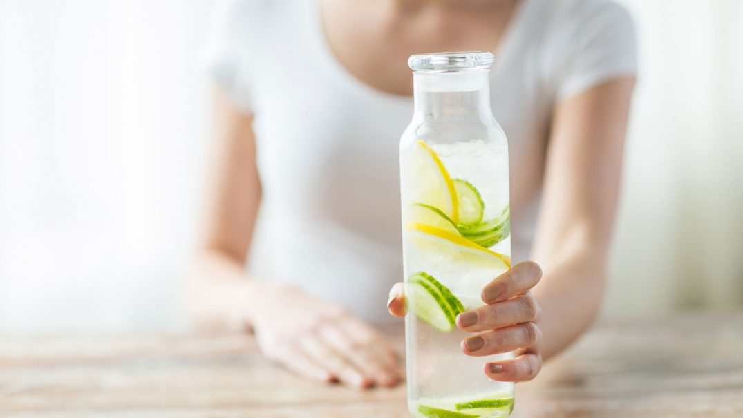 woman holding water with lemon and cucumber